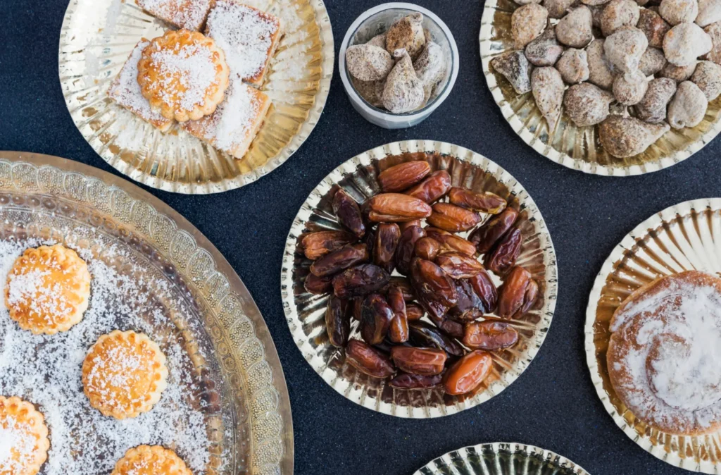 Assorted Middle Eastern desserts on decorative golden trays, featuring date cookies, dried figs, and sweet pastries.